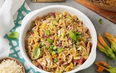 Farfalle con zucchine novelle, prosciutto di San Daniele, fiori di zucca e Grana Padano Riserva