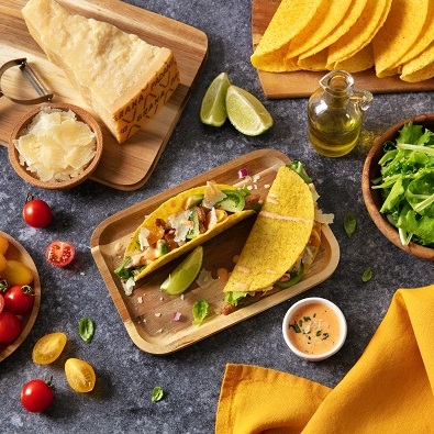 Marinierte Hähnchen-Tacos, gefüllt mit Avocado, bunten Tomaten, Pflücksalat, roten Zwiebeln, gehobeltem Grana Padano und pikanter Grana Padano-Creme